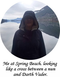 Me at Spring Beach, looking like a cross between a nun and Darth Vader, with a lake and mountains in the background